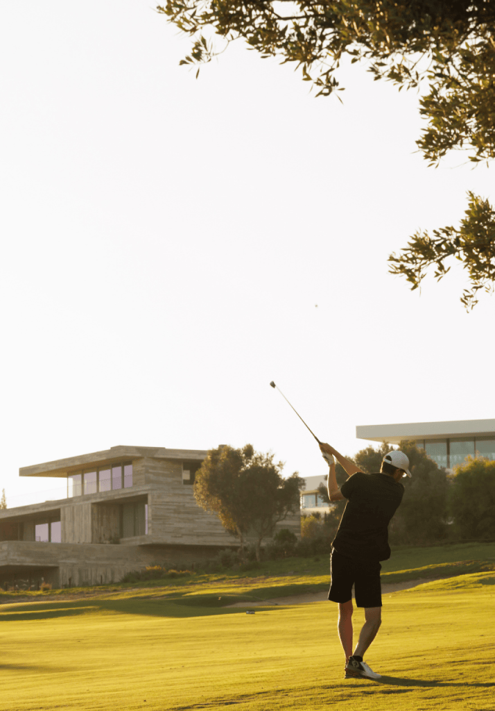Estilo de vida ativo no Palmares Resort, com jogador de golfe em ação ao entardecer junto a villas de design contemporâneo.