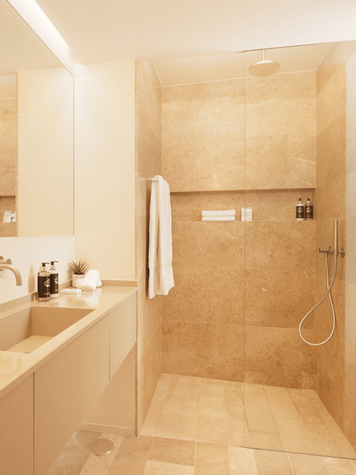 Casa de banho com revestimentos em pedra natural e design elegante nos Palmares Signature Apartments — funcionalidade aliada à estética.
