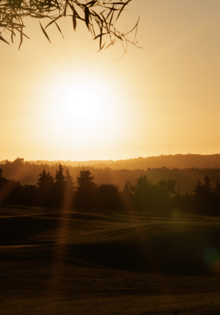 Pôr do sol sobre o campo de golfe de Palmares, criando uma atmosfera serena e inspiradora no Algarve.